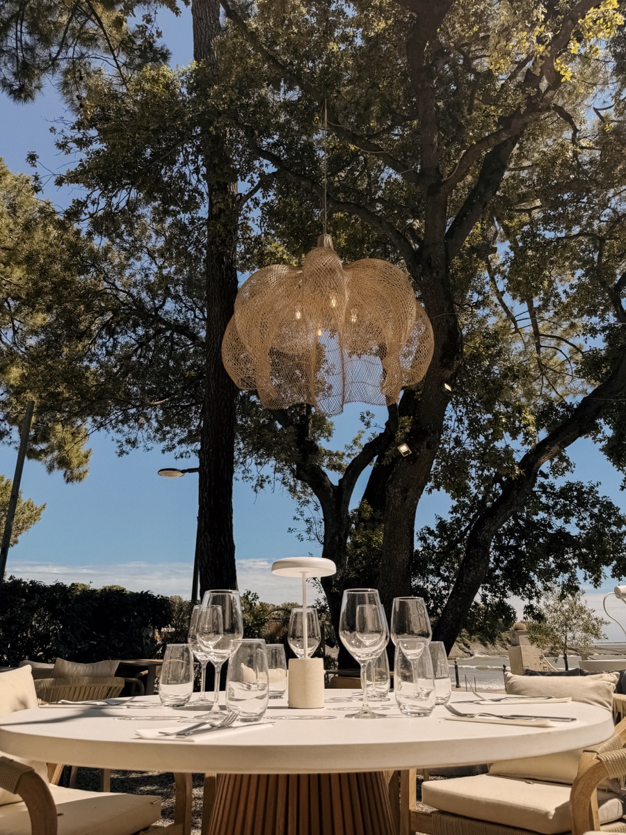 Table dressée sous un lustre entre les arbres à la Pergola